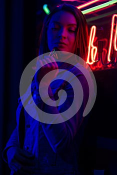 Creative sexual portrait of a girl in neon lighting with glasses, night party, dancing, game business, striptease