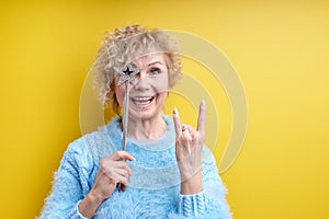 creative shot of beautiful crazy senior woman with magic wand, showing rock gesture