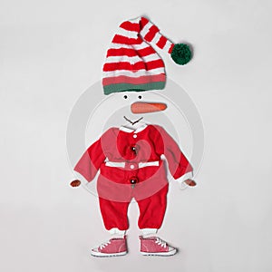 Creative snowman shape made of Santa elf`s hat, red suit and different items on white background, flat lay