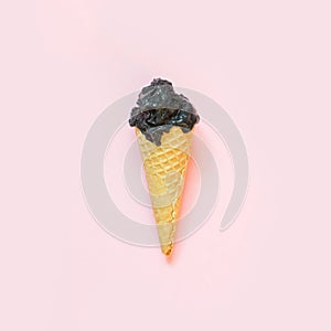 Creative still life of black ice cream in waffle cone on pink background. Spring concept. Top view.