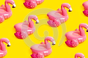Creative summer beach concept. Pattern from Inflatable pink mini flamingo on yellow background, pool float party. Flat lay, copy