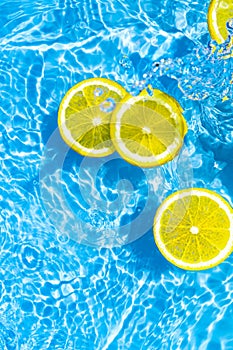 Creative summer composition made of sliced lemon in transparent blue water. Refreshment concept. Healthy refreshing drink theme.