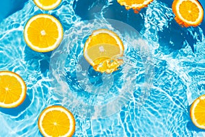 Creative summer composition made of sliced orange in transparent pool water. Refreshment concept. Healthy refreshing drink theme.