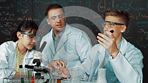 Creative teacher pointing at blackboard while talking to smart boy. Edification.