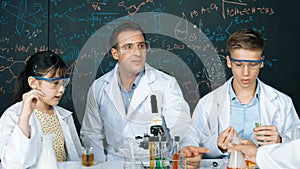 Creative teacher pointing at blackboard while talking to smart boy. Edification.