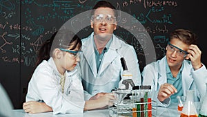 Creative teacher pointing at blackboard while talking to smart boy. Edification.