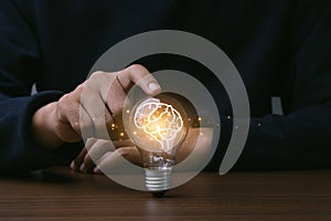 Creative thinking idea for Technology concept.Hand of man touching light bulb with orange glowing and brain icon.Idea concept