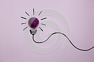 Creative thinking ideas and innovation concept. A ball of purple threads with a light bulb symbol on a purple background