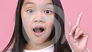 Creative thinking and inspiration. Close up portrait of little asian girl having idea, pointing finger up and smiling