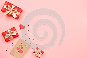 Creative Valentine`s Day greeting card with red decorations and gift boxes, golden heart confetti on pink background, copy space,