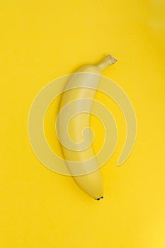 Creative view of a banana on a paper yellow background.