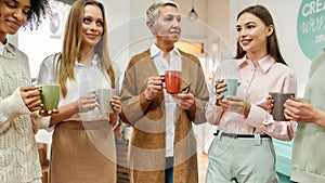 Creative and well-dressed group of women of different age together drinking coffee smiling and speaking to each other