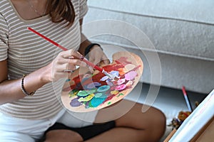 Creative woman holding painting brush and mixing color oil painting on palette.