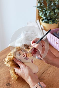 Creative woman painting handmade doll face