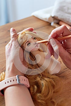 Creative woman painting handmade doll face