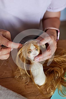Creative young adult woman making handmade doll
