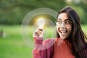 Creative young woman hold shinning light bulb.