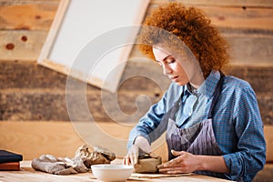 Creative young woman potter making earthen dishes in workshop