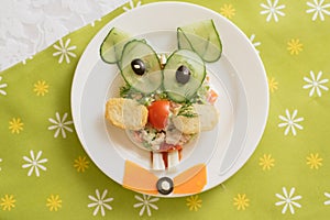 Creatively decorated salad in the form of a hare. Children`s menu on a green background.
