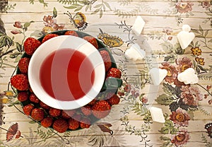 Creatively served fruit tea and strawberries on saucer