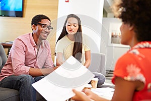 Creatives Having Informal Meeting On Sofas In Design Studio