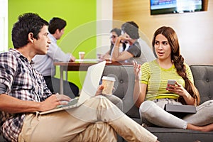 Creatives Having Informal Meeting On Sofas In Design Studio