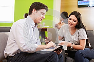 Creatives Having Informal Meeting On Sofas In Design Studio