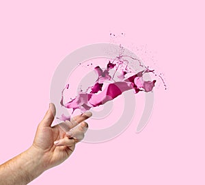 Creativity concept hand throwing paint on light pink background