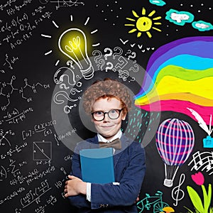 Creativity education. Clever child boy in suit and glasses holding textbook on science and arts occupations pattern background