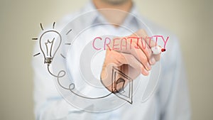 Creativity, Glowing Bulb Concept, Man writing on transparent screen