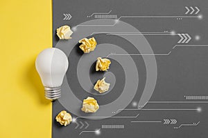 Creativity inspiration, great business idea concept with white light bulb and paper crumpled ball on gray and yellow background.