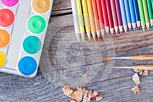 Creativity: Multi-colored pencils, water colors and brushes on rusty wooden table