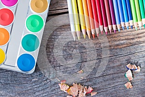 Creativity: Multi-colored pencils, water colors and brushes on rusty wooden table