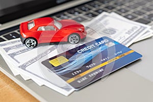 Credit card, Car model and Notebook on wooden desk. shopping online and car payment by using laptop