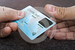 Credit card has built-in fingerprint scanner. Illustration of biometric payment security. One male hand is holding blue card and photo