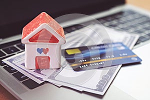 Credit card, House model and Notebook on wooden desk. shopping online and house payment by using laptop