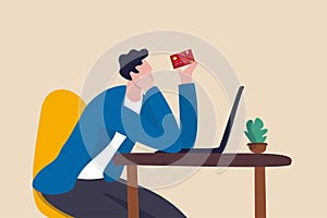 Credit card online payment, e-commerce or internet shopping concept, contemplation man looking at his credit card about to using