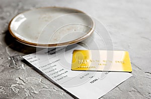 Credit card for paying, plate and check on cafe stone desk background