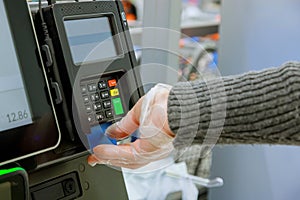 Credit card payment terminal in shop on human hand in gloves respecting health standards of Coronavirus COVID-19