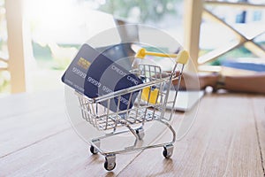 Credit card in shopping cart on wooden table with laptop, shopping concept