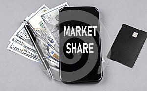 Credit card and text MARKET SHARE on smartphone with dollars and pen. Business concept