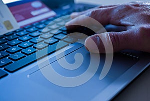 Credit card thief working on passwords on laptop computer keyboard, conceptual image of fraud