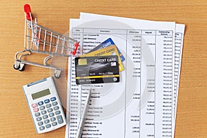 Credit cards and Cart supermarket and Calculator on Bank statement on a Wooden table