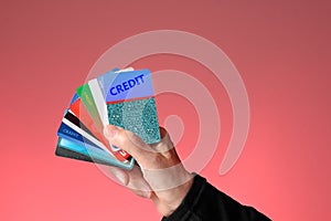 Credit cards held in female hand. Red-pink background