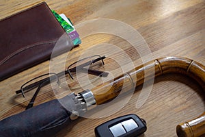 Credit cards in wallet, keys, black glasses, stylish umbrella on wooden table