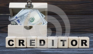 CREDITOR word on cubes with a chest of money against a dark background