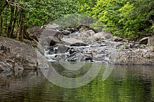 A creek cascades into a pool at a popular tourist destination in the tropics