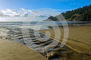 A creek flows into the Pacific Ocean at Oswald State Park, Oregon, USA