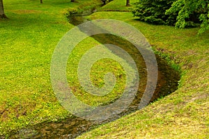 Creek on a green lawn in the park.