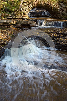 Creek with waterfalls and an old arch bridge